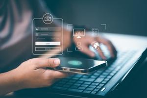 Main tenant un smartphone avec interface de connexion et empreinte digitale, devant un ordinateur portable, illustrant la cybersécurité et l'authentification.