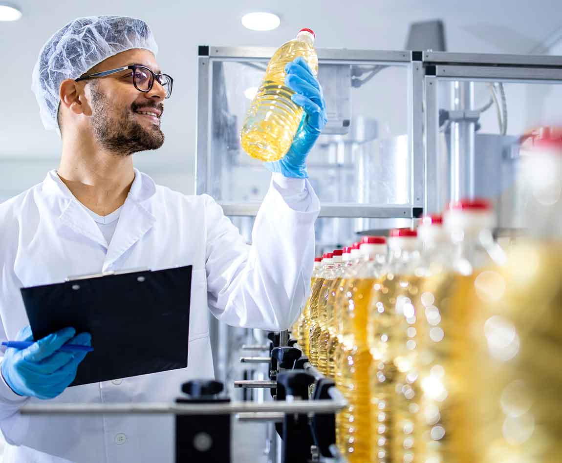 Un employé d'une usine contrôle une ligne de production de bouteilles d'huile