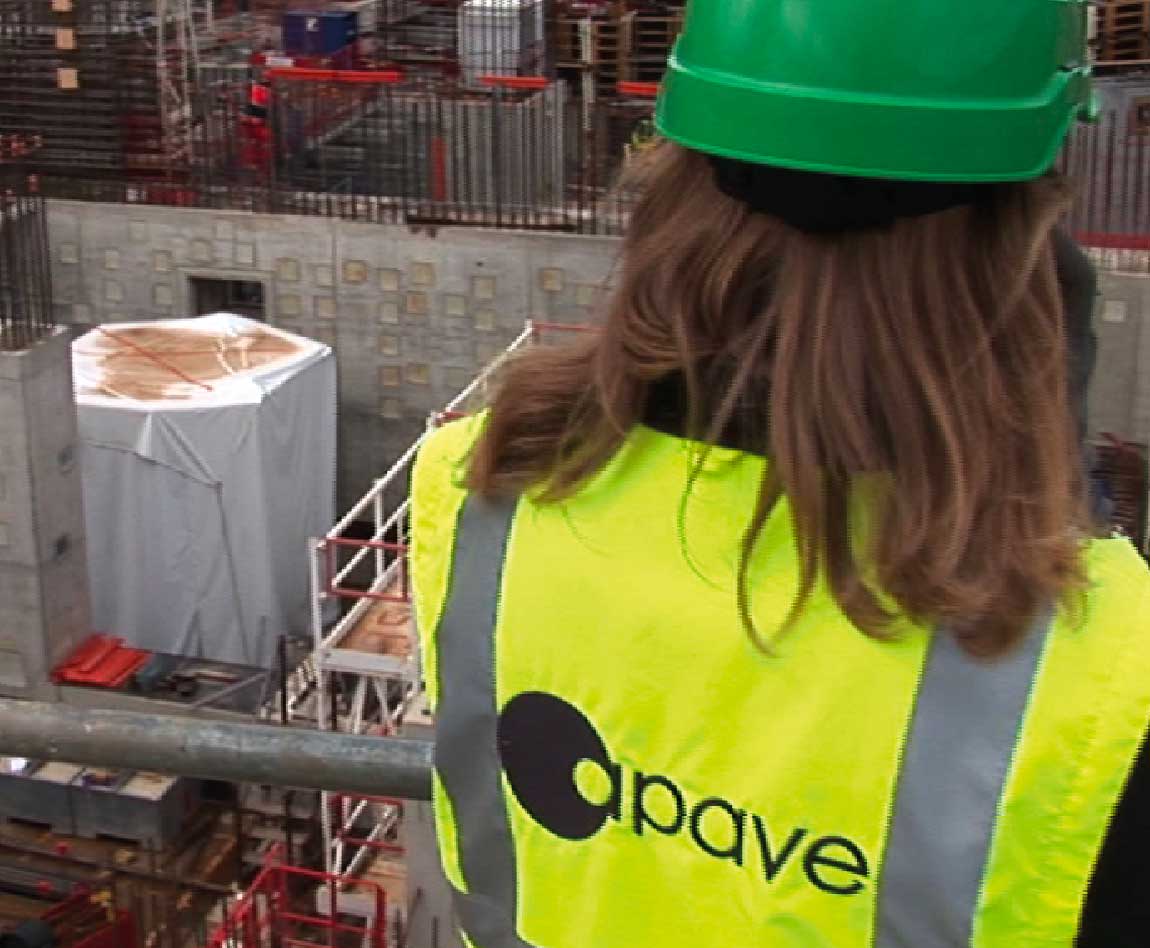 Une femme avec un casque et un gilet de sécurité Apave sur un chantier